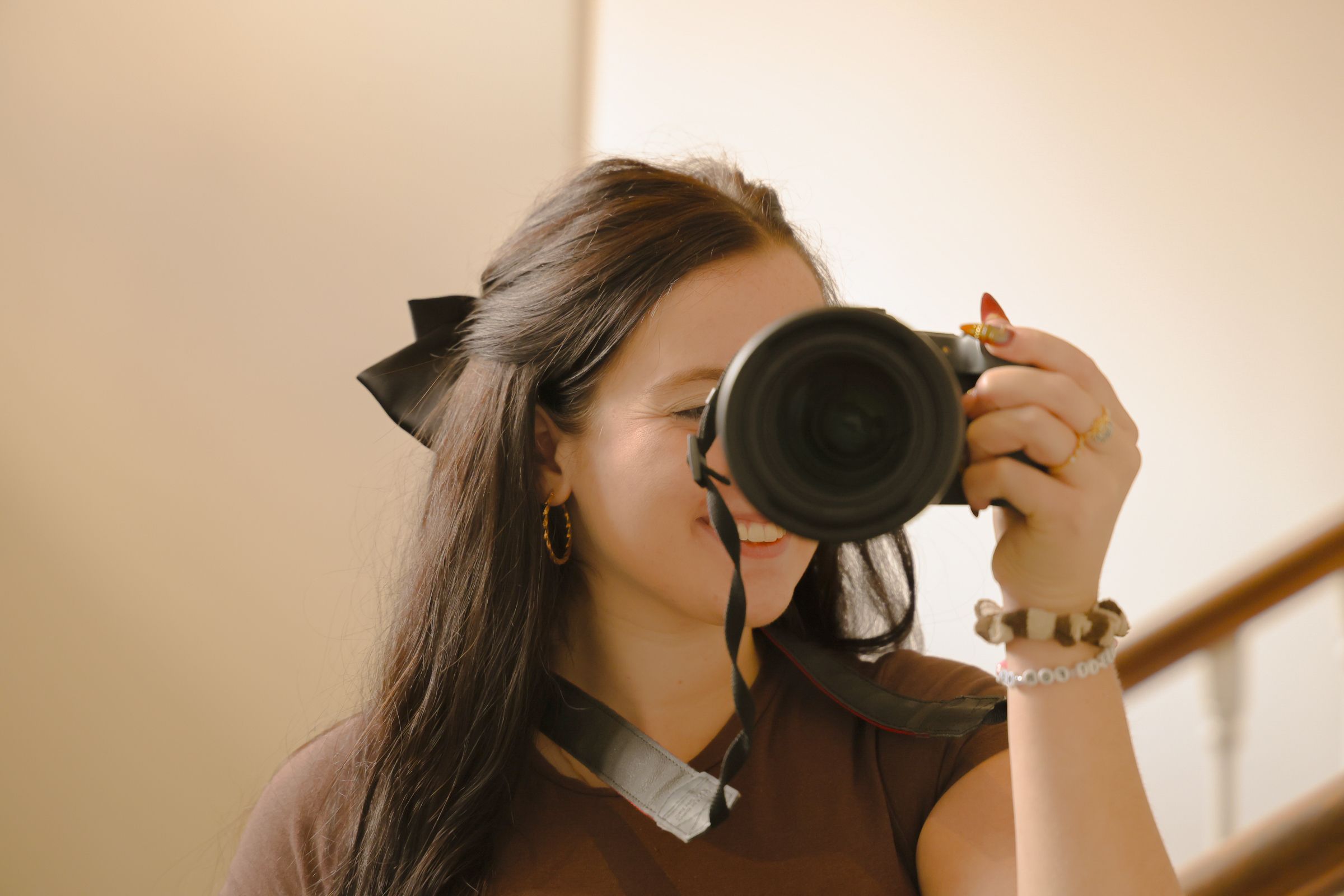 A photographer holding her camera and smiling in a mirror photo
