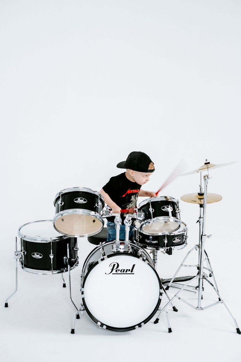 A sequence of three photos showing a drummer performing on a black and white drum kit against a white background.