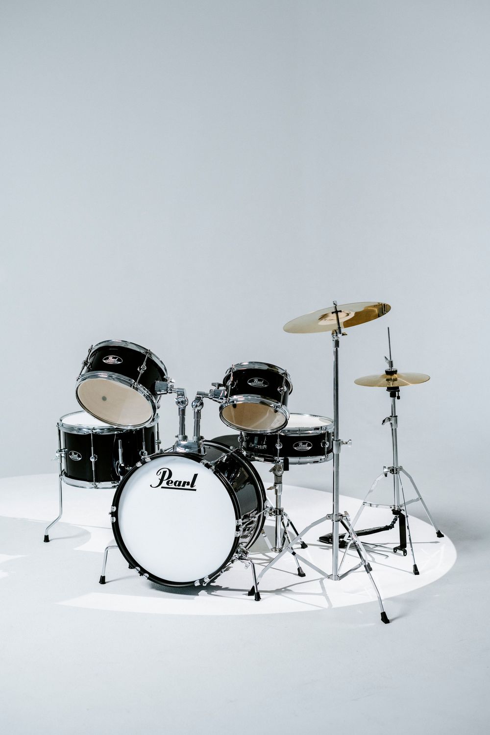 A black Pearl drum kit with cymbals set up on a white background for a studio photography session.