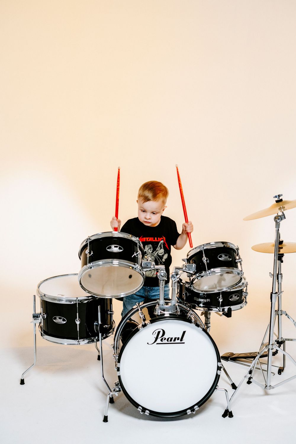 A sequence of four images showing a black Pearl drum kit being assembled from left to right on a white background.