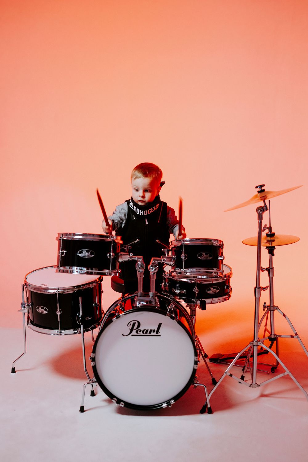 Pearl drum kit photographed in sequence with orange gradient lighting against white background showing multiple angles.