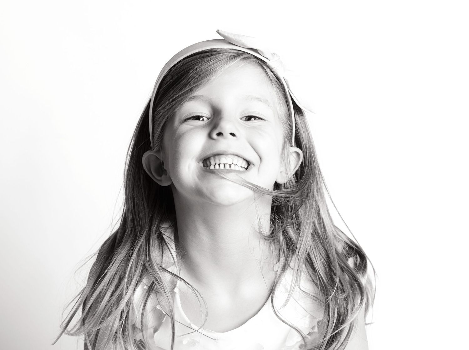 Four black and white portraits show a person making different playful expressions while laughing.