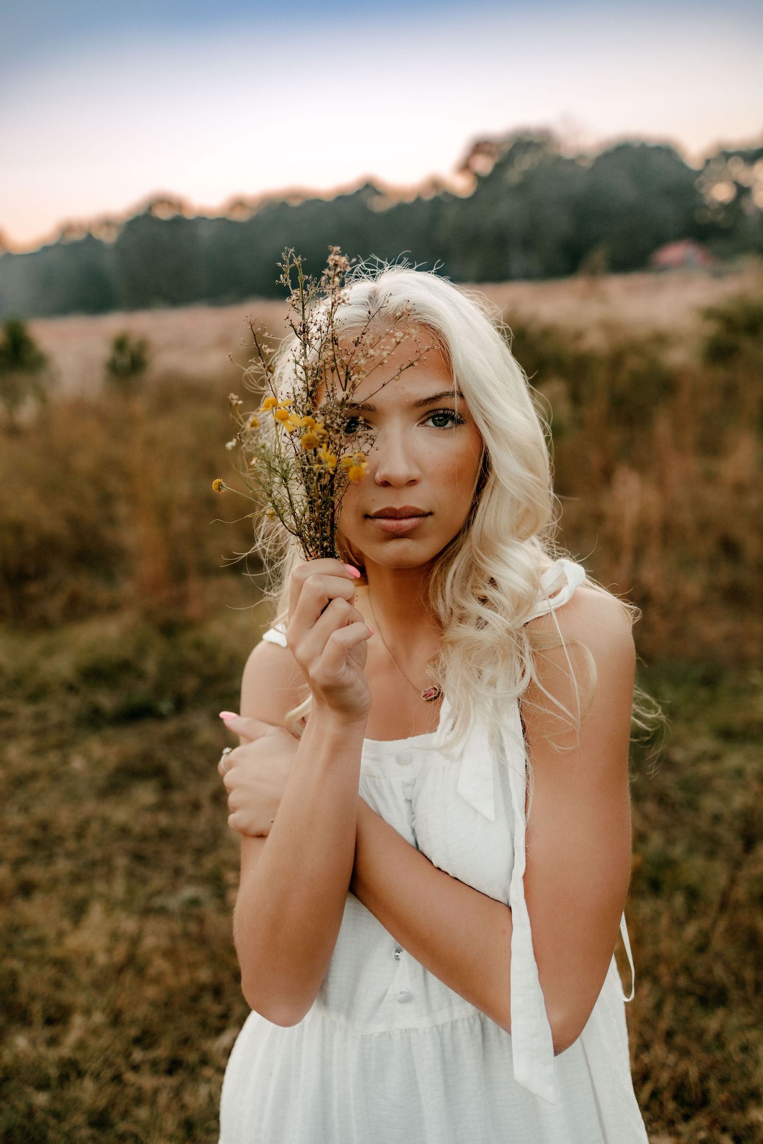A dreamy portrait series of a person in a white dress with wildflowers in their blonde hair at sunset.