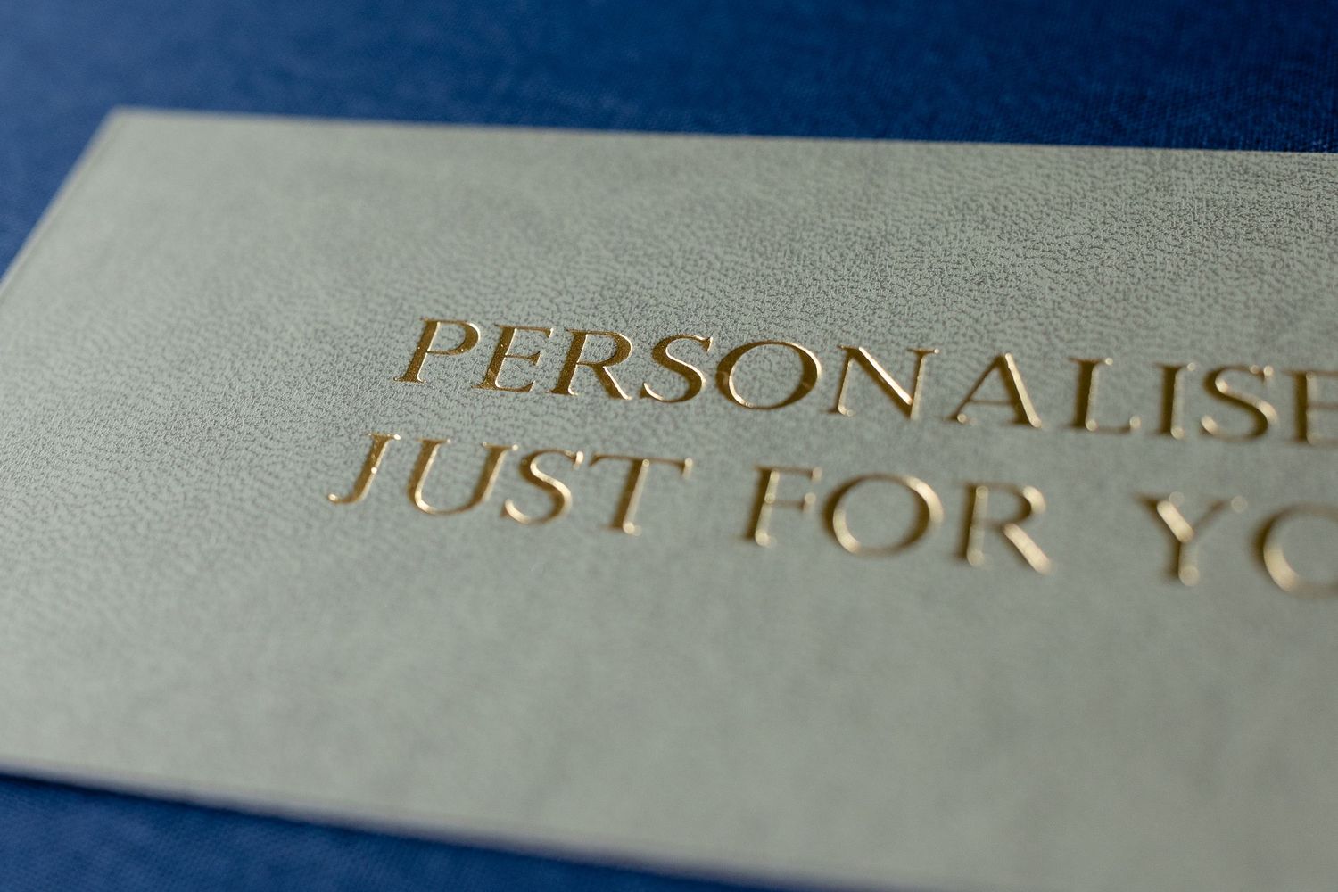 Close-up macro shot of gold metallic text printed on a light gray textured paper surface.
