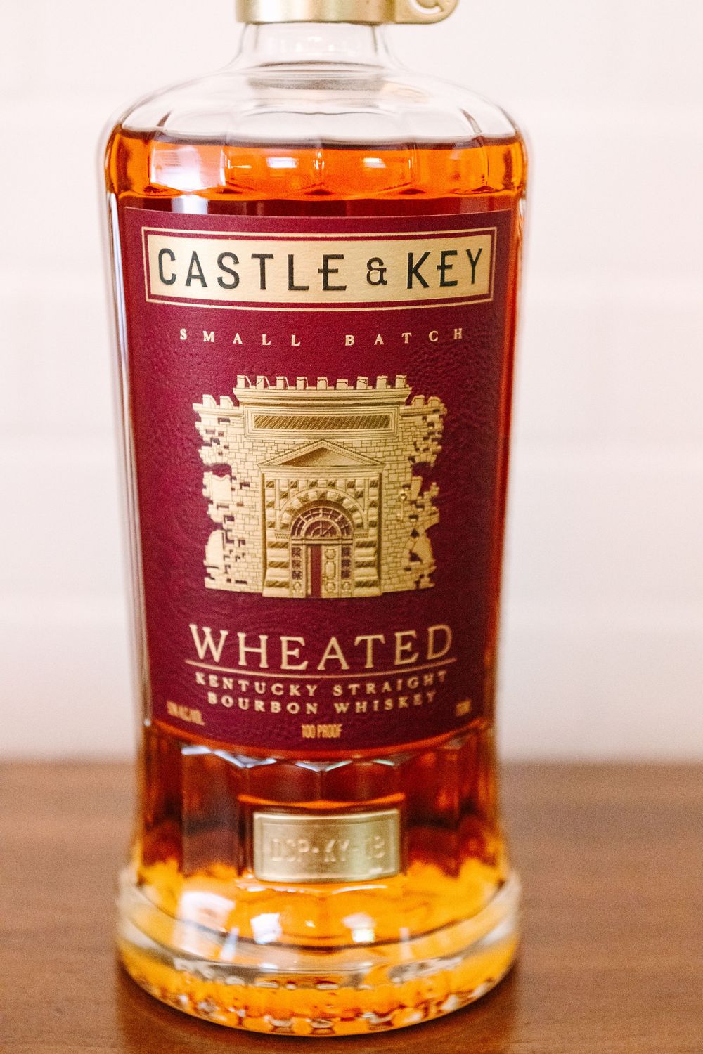 Close-up view of amber colored whiskey bottles with gold lettering displayed on a wooden surface.