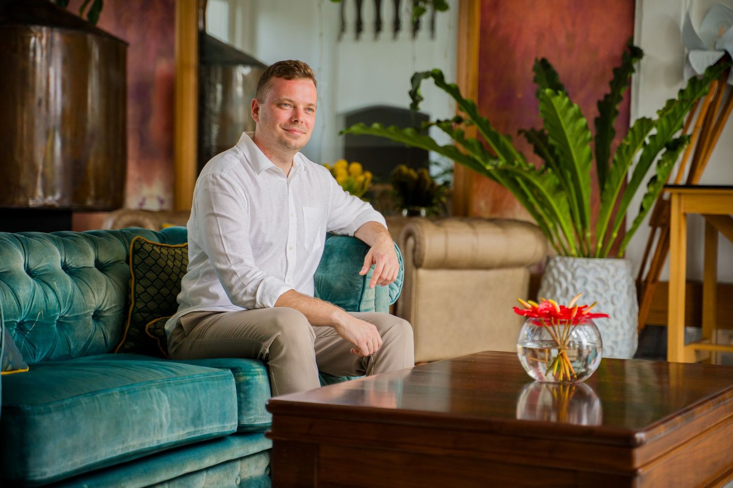 Professional headshots of someone in a white shirt sitting on a teal couch in a bright modern office setting. Shot by Luminair Studio