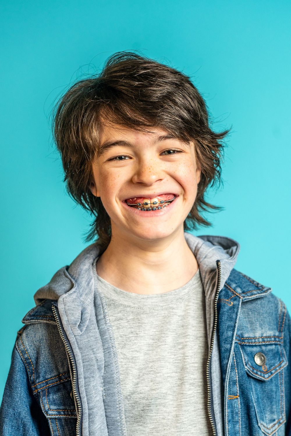 A sequence of expressions shows someone in a denim jacket and gray shirt against a bright turquoise background.