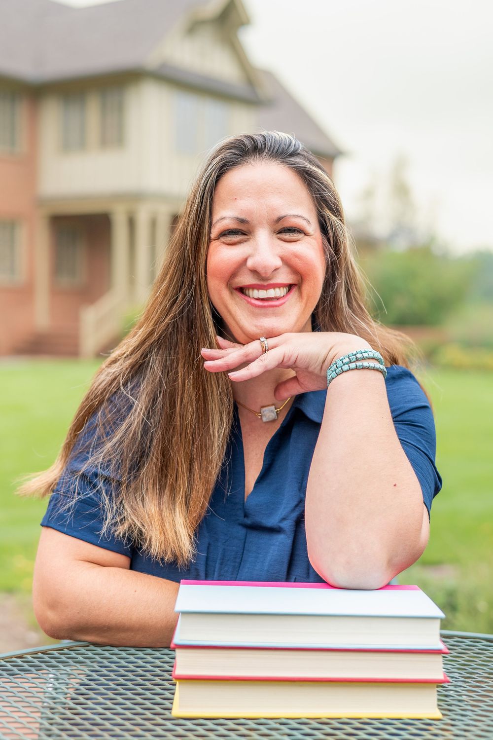 Three photos of a person in a blue top smiling and leaning on books at an outdoor table.