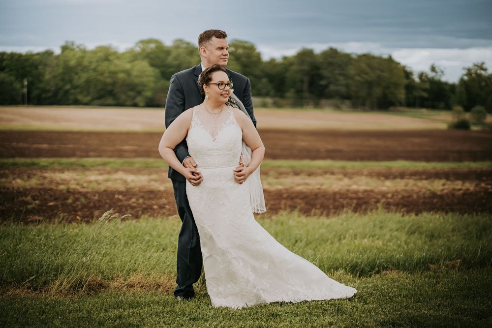A wedding dress train flows gracefully across an outdoor field during a photo session.