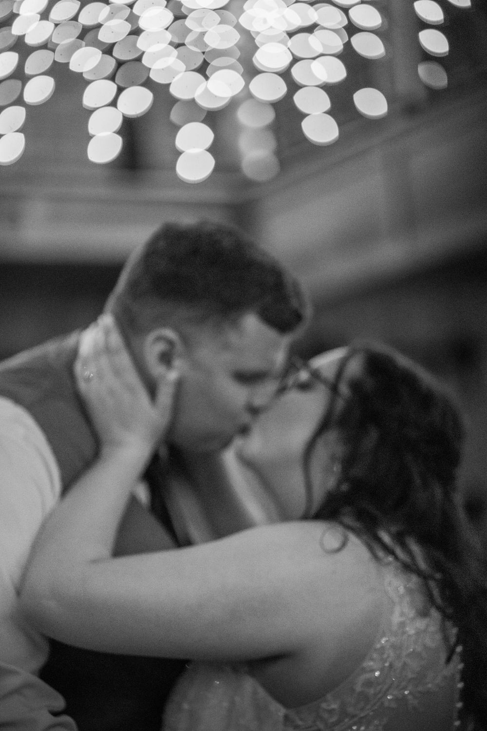A black and white wedding photo series under twinkling reception lights showing an intimate dance moment.
