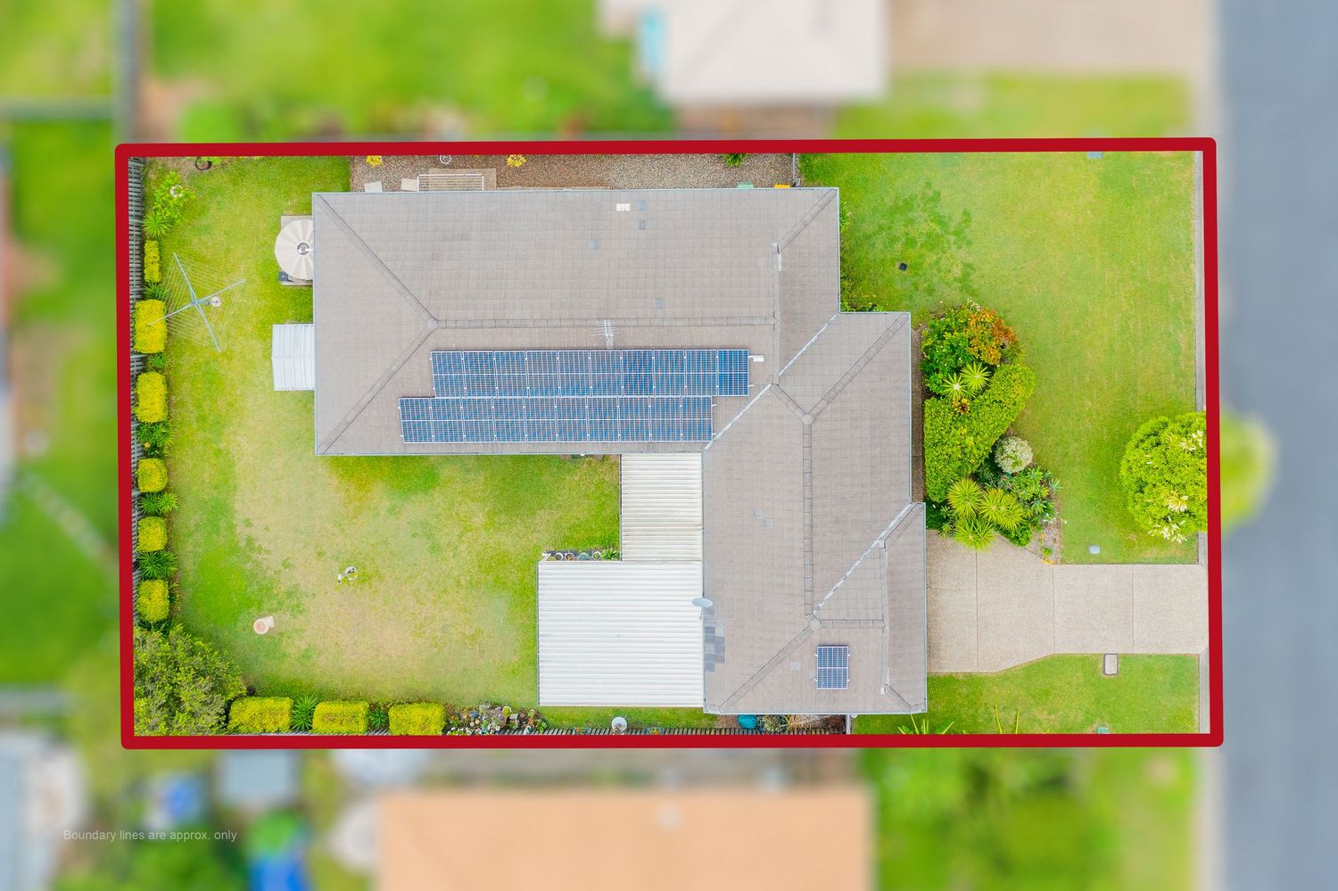 Aerial view of a home with solar panels on a suburban block with red boundary lines marking the property.
