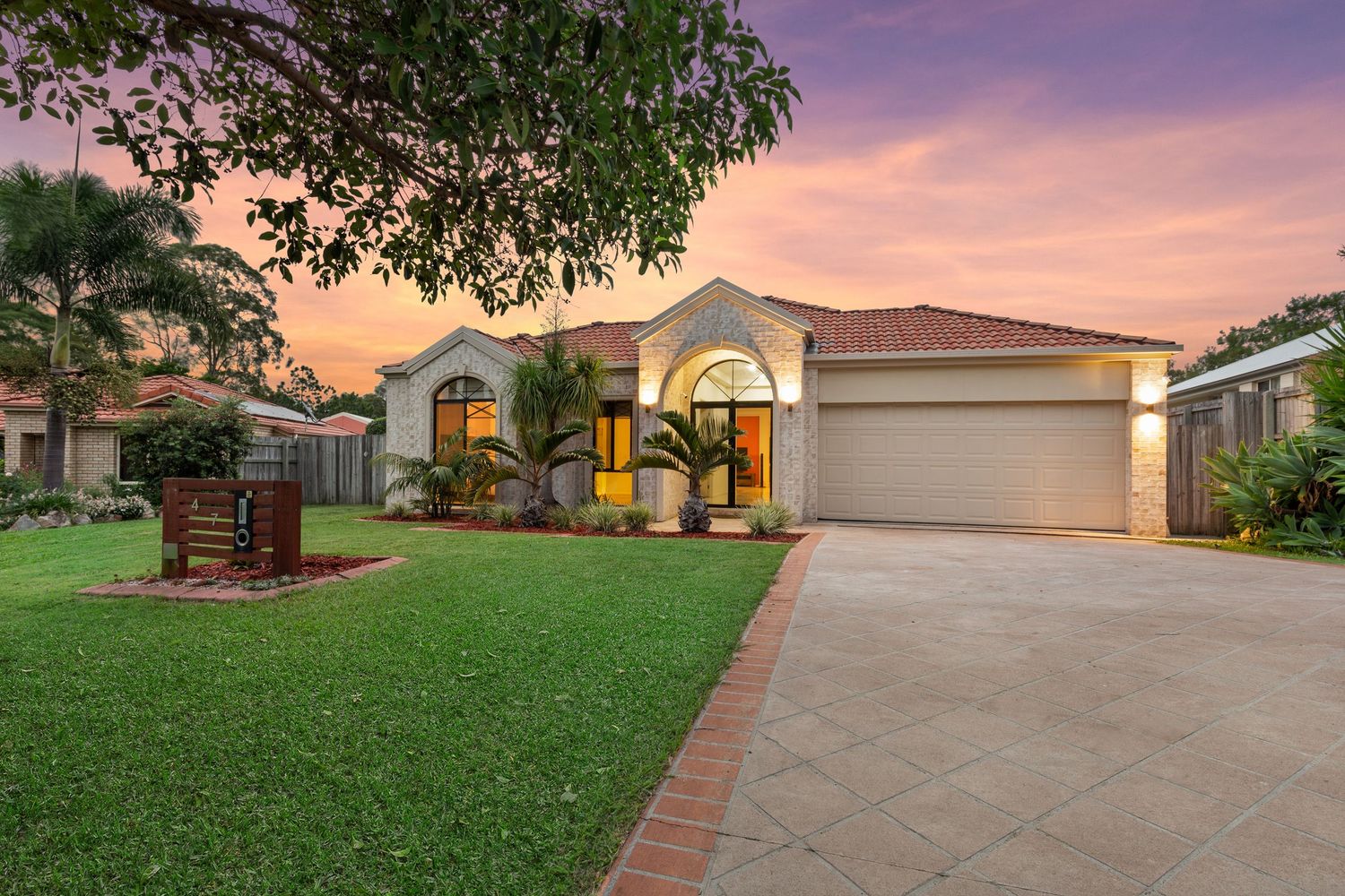 Charming rendered brick home with terracotta roof and manicured front lawn at dusk.