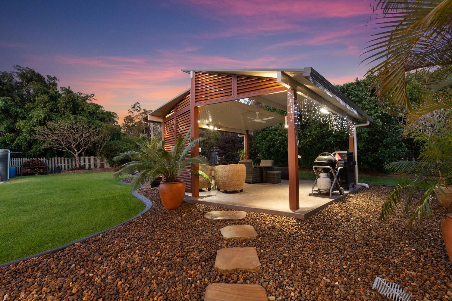 Elegant timber pergola with string lights and stepping stone path through landscaped garden.