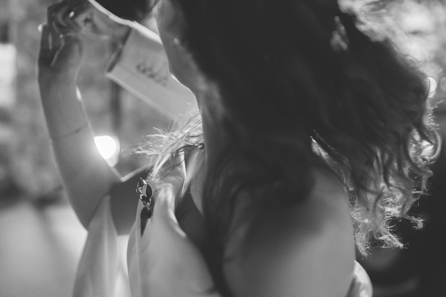 Black and white image of Santorini destination wedding bride dancing which conveys motion.
