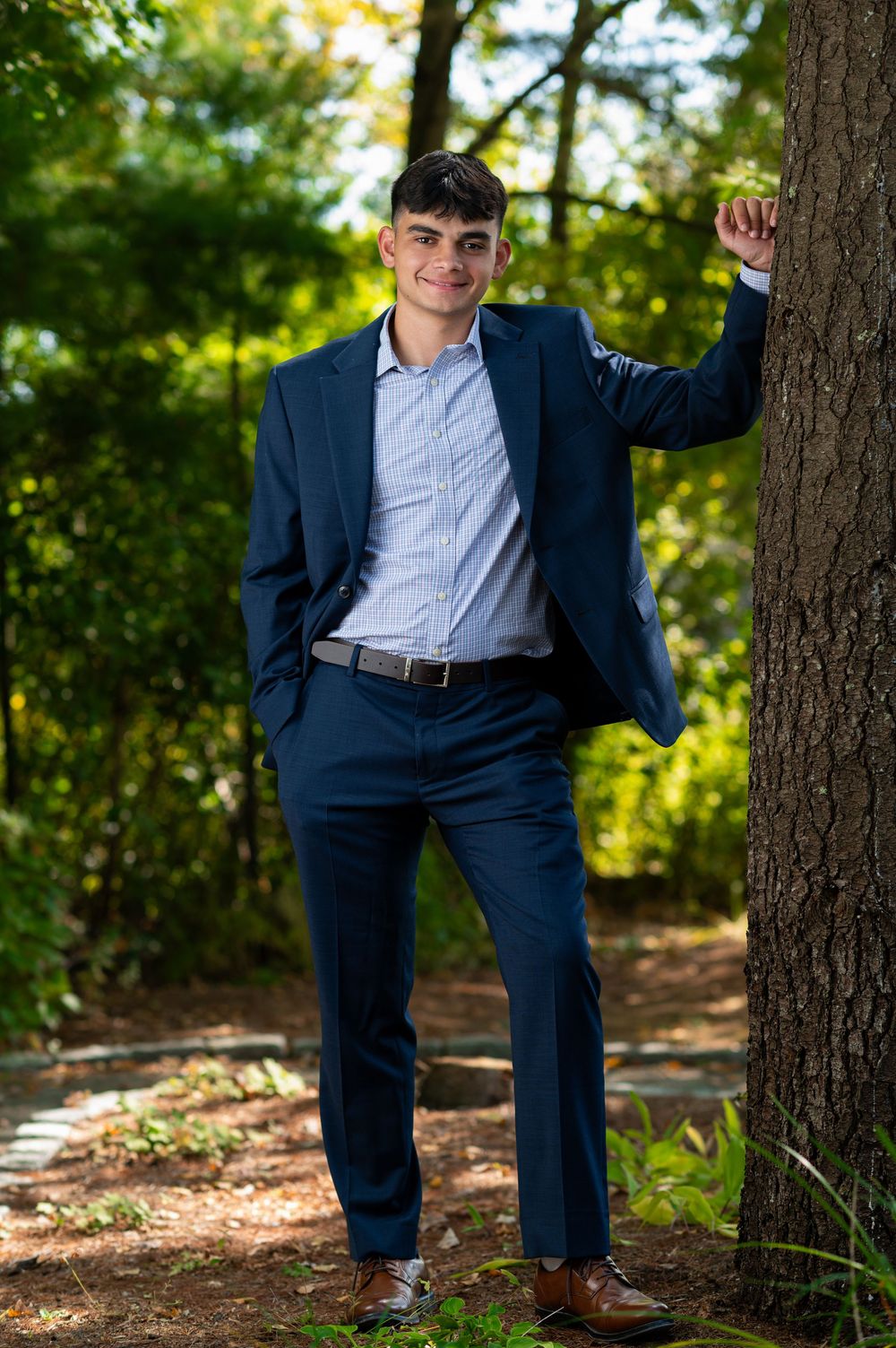 Outdoor portrait session featuring navy suit against natural wooded background.