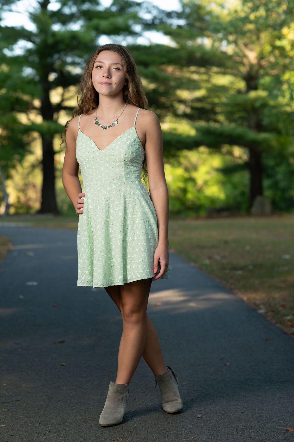 Outdoor portrait in mint green dress along tree-lined path.