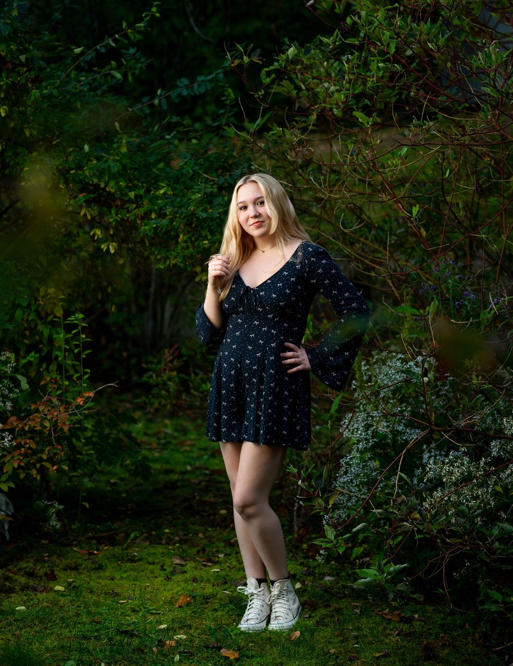 Portrait session in navy polka dot dress against natural wooded backdrop.