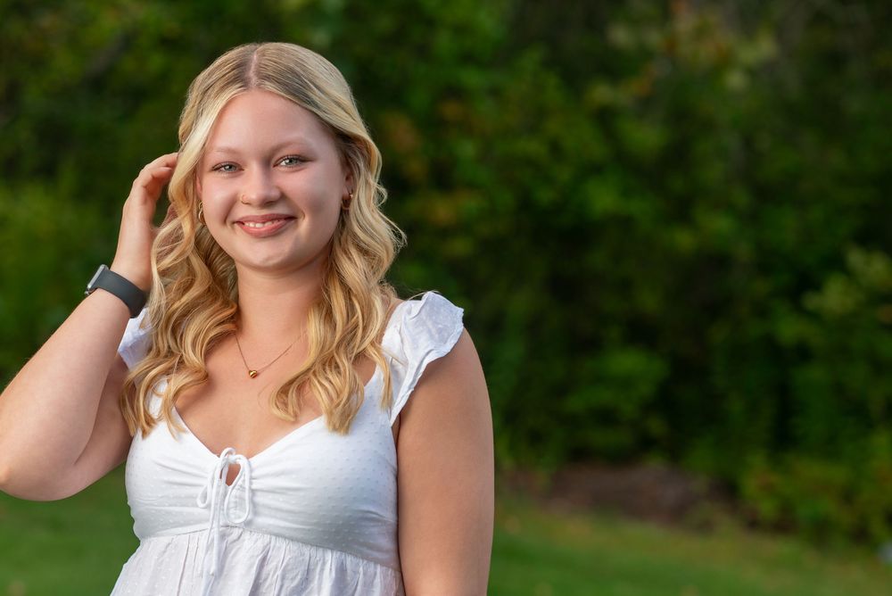 Portrait session outdoors with soft lighting and green foliage background.