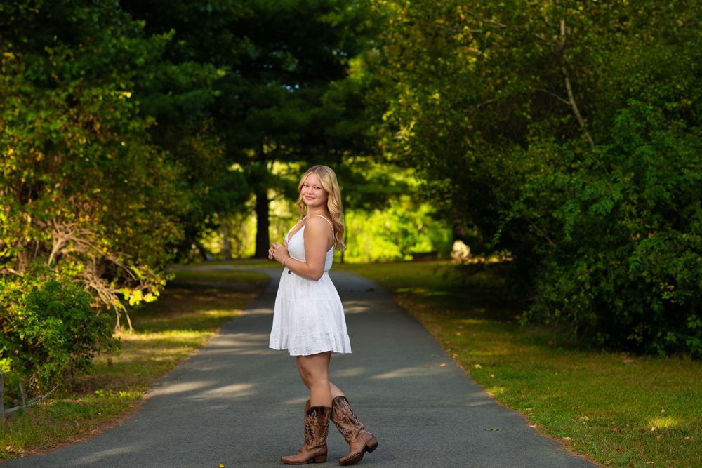 Outdoor photoshoot on tree-lined path with natural lighting.