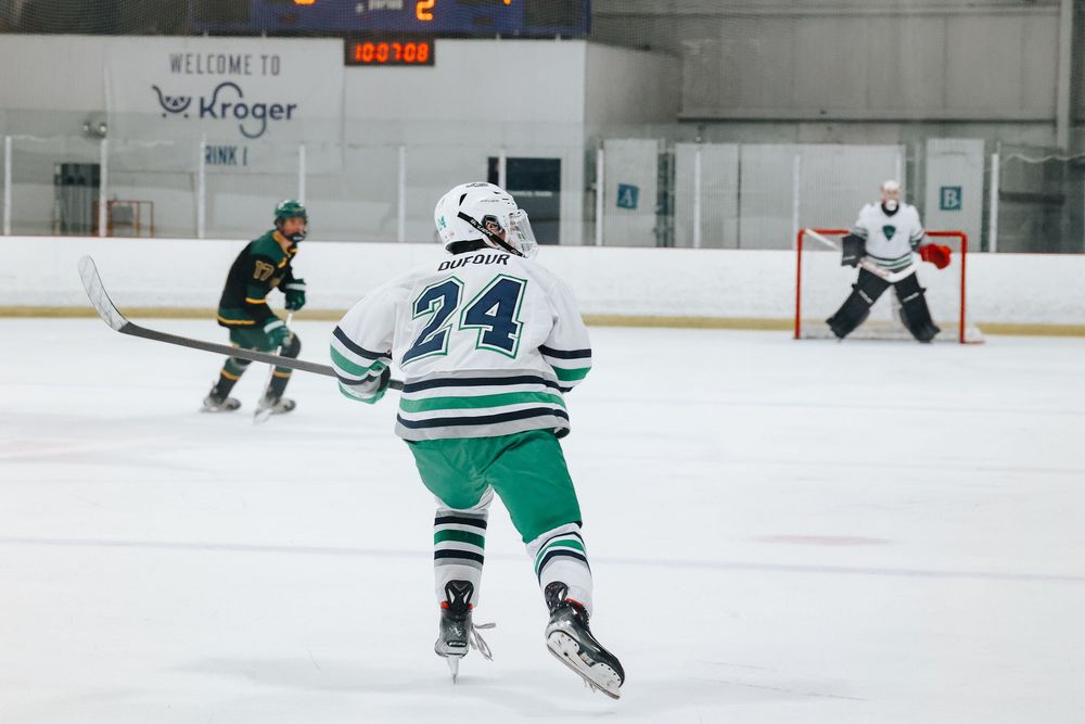Hockey players in green and white jerseys skating on an ice rink during a game.