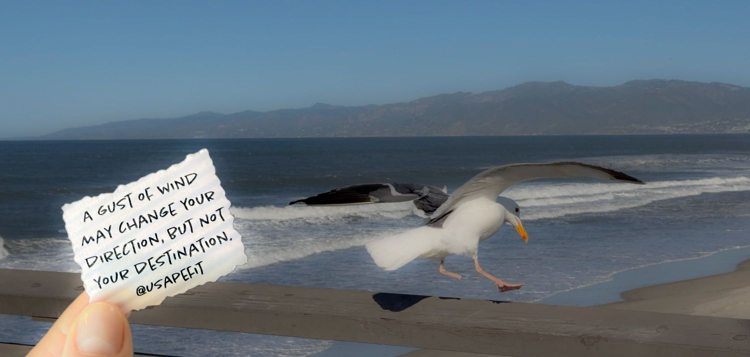 A panoramic sequence of coastal beach scenes showing waves, mountains, and handwritten notes on paper against a sandy backdrop.