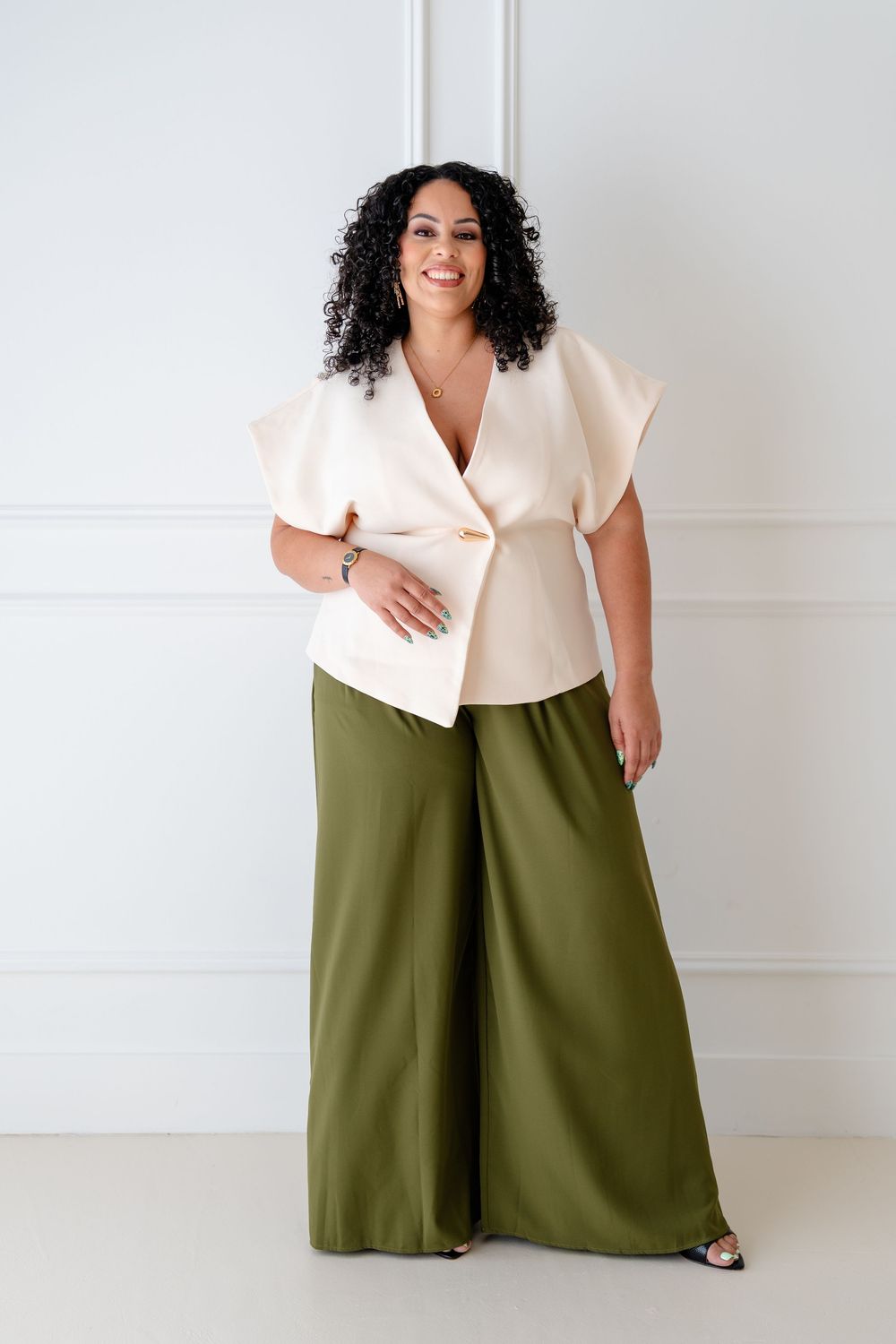 Four fashion photos showing olive green wide-leg pants paired with a cream colored top in different poses against white wall.