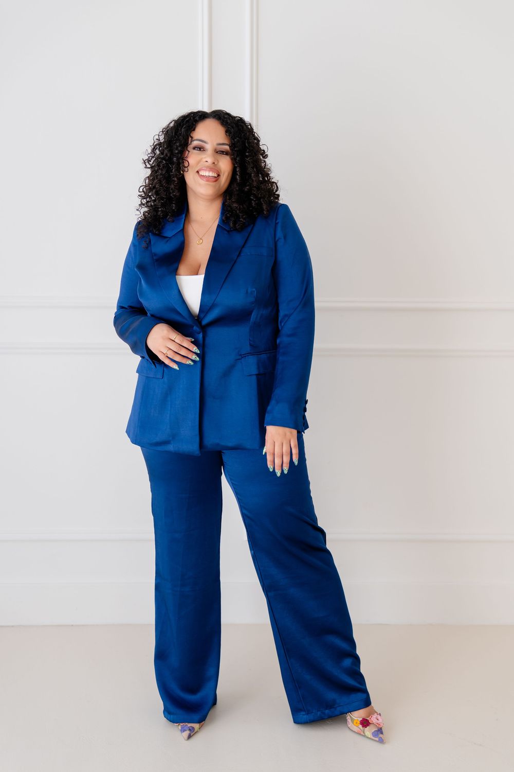 Professional wearing a royal blue power suit with wide-leg pants poses confidently against a white backdrop.