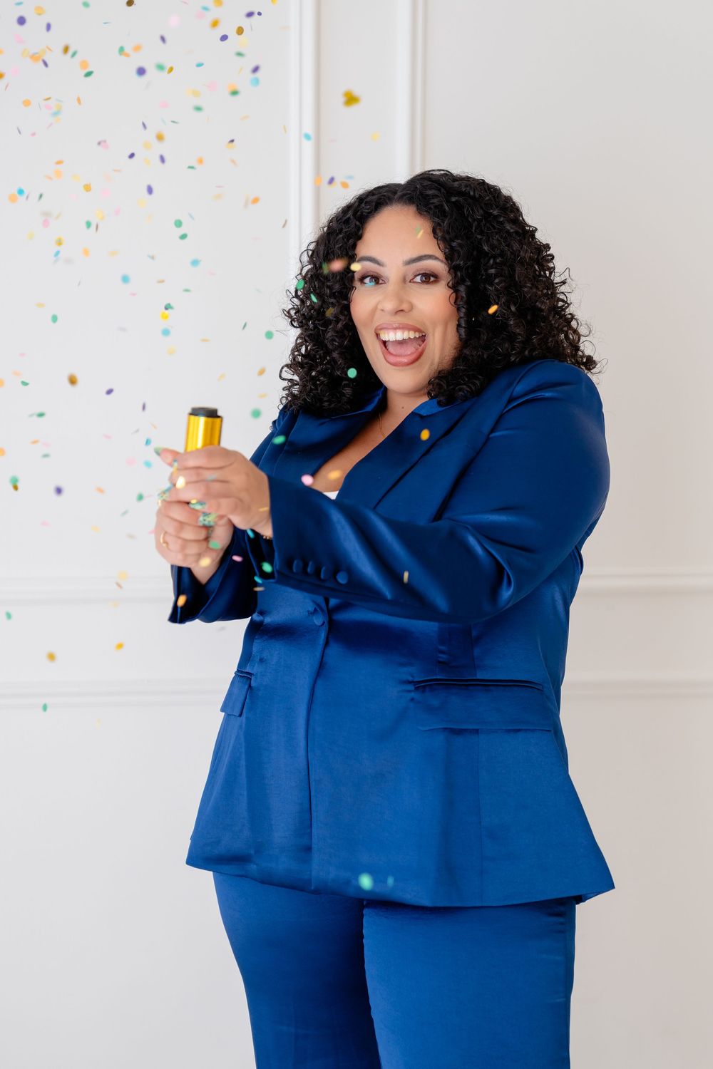 Person in royal blue business suit celebrating with confetti against white background in multiple poses.
