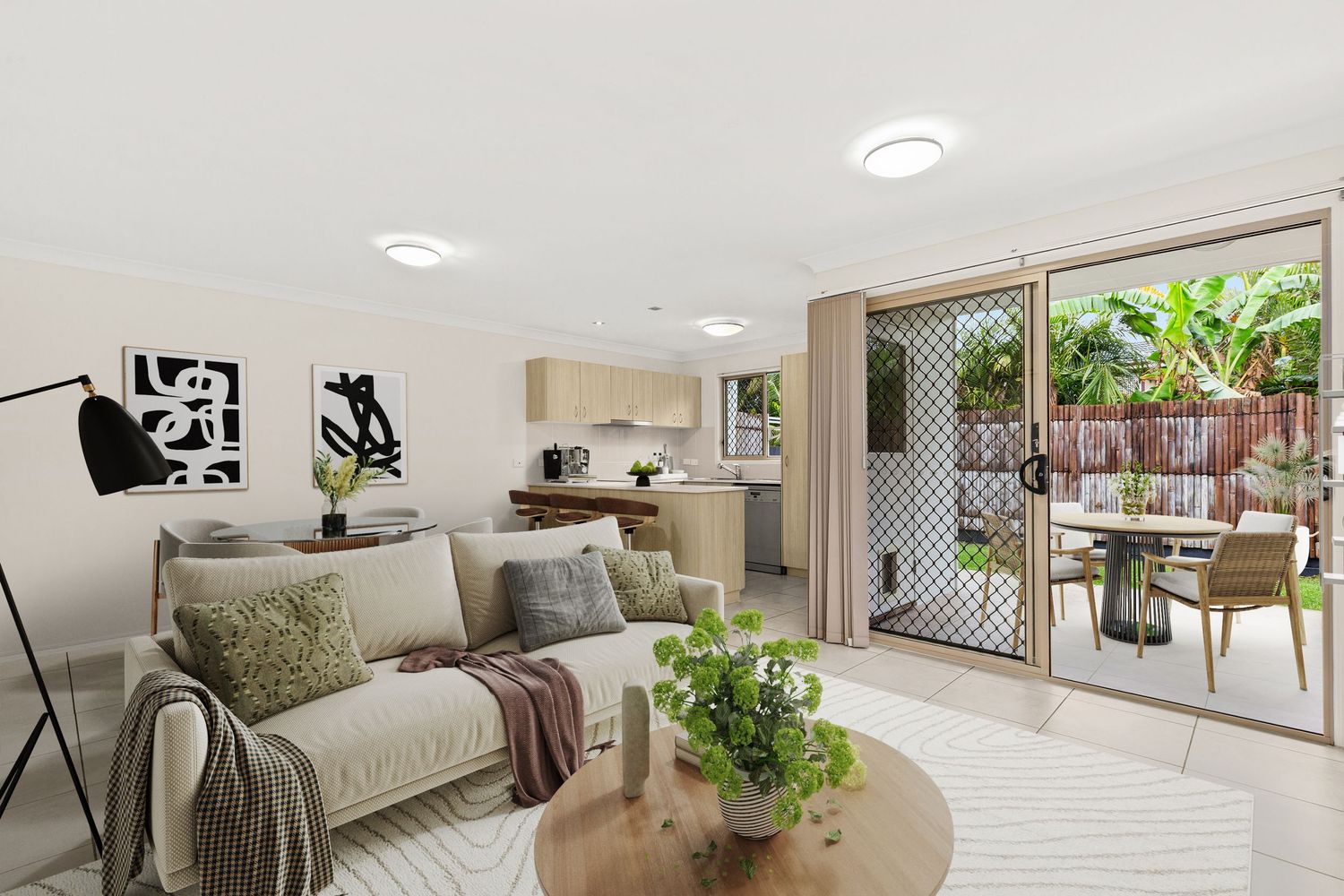 Bright open-plan living room with neutral sofa, timber coffee table, and sliding doors opening to an outdoor dining area.