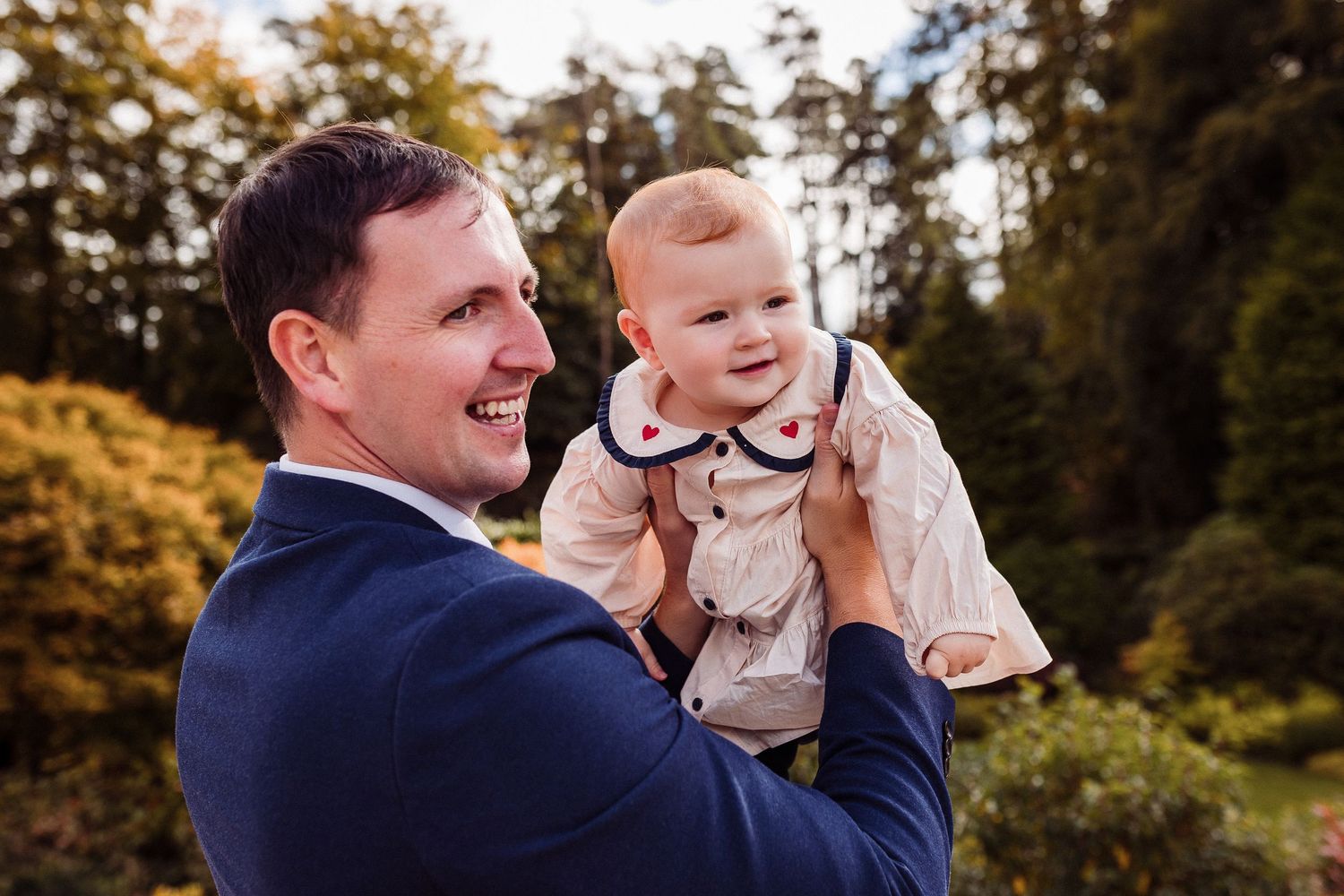 A parent and child share joyful moments together outdoors during a golden autumn photoshoot.