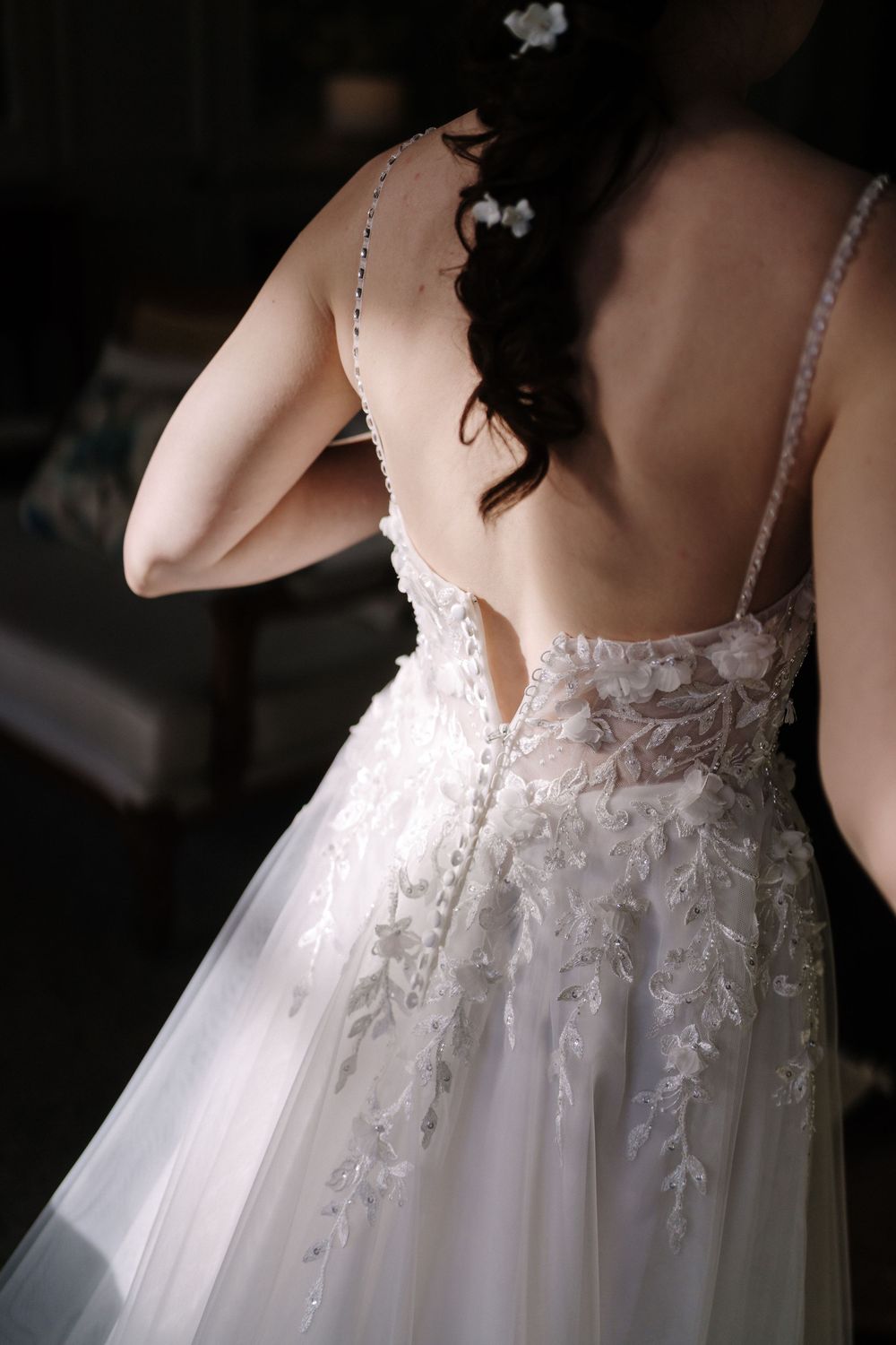 Close-up details of a delicate white wedding dress with intricate lace appliques and sheer fabric.