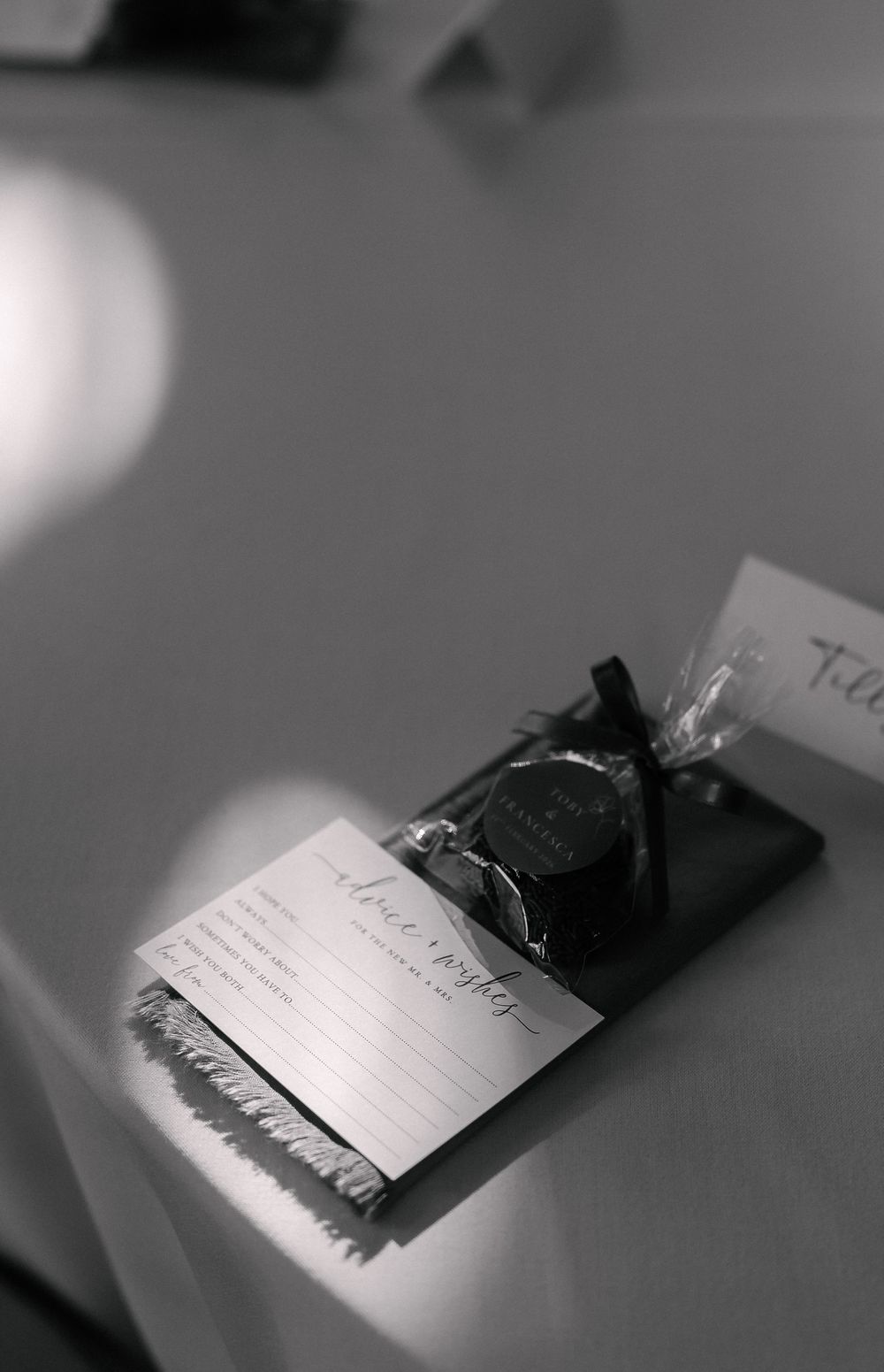 A black and white artistic photograph shows a handwritten note or letter in soft focus with blurred edges.