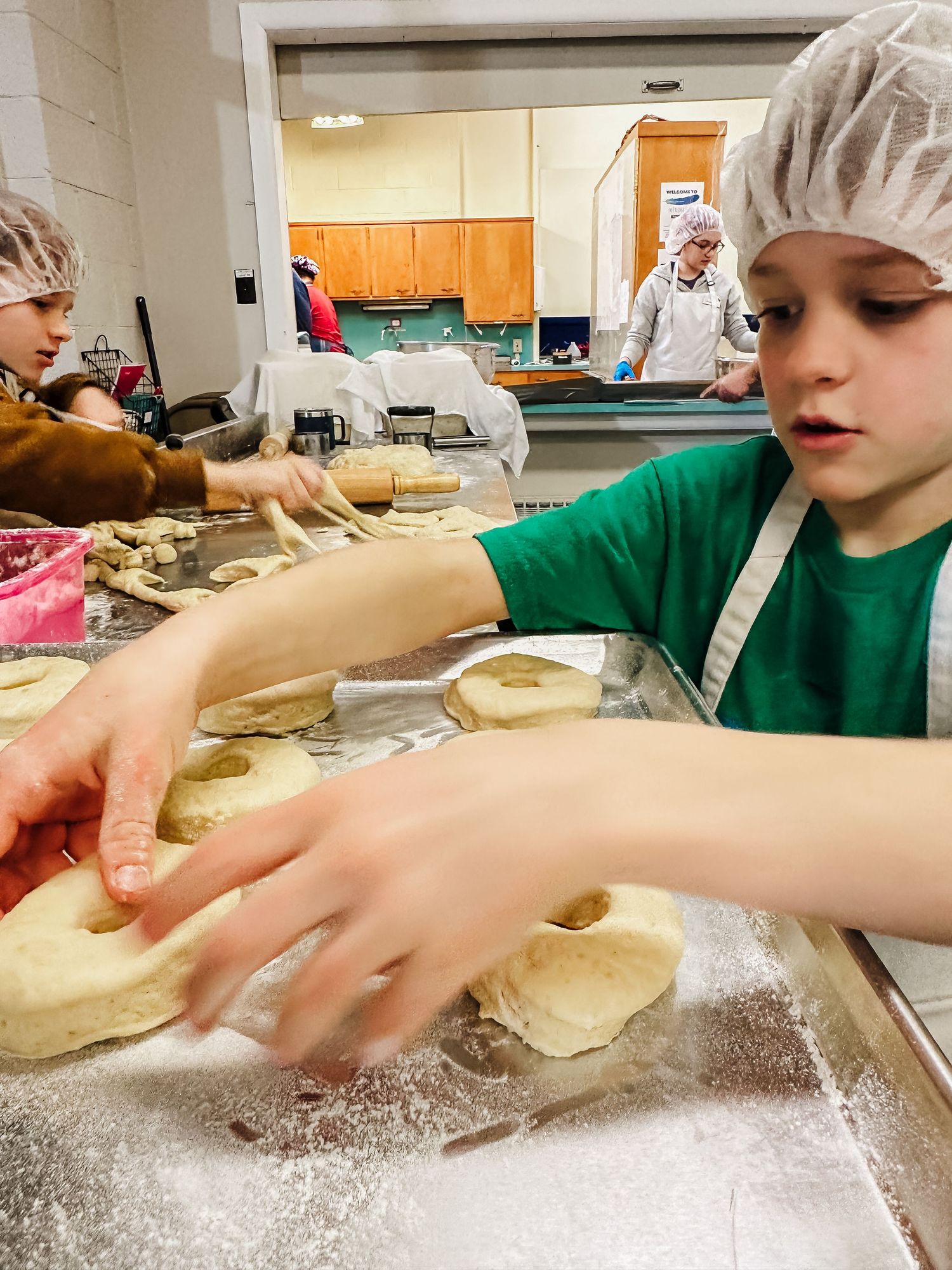 Young boys helping with donut preparation, cutting the dough into round shapes.
