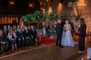 Wedding guests gather on a dance floor under warm lighting at an elegant indoor reception venue.