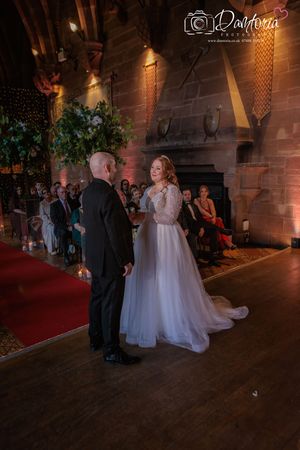 Wedding ceremony in a dimly lit stone castle venue with romantic mood lighting and elegant decor.