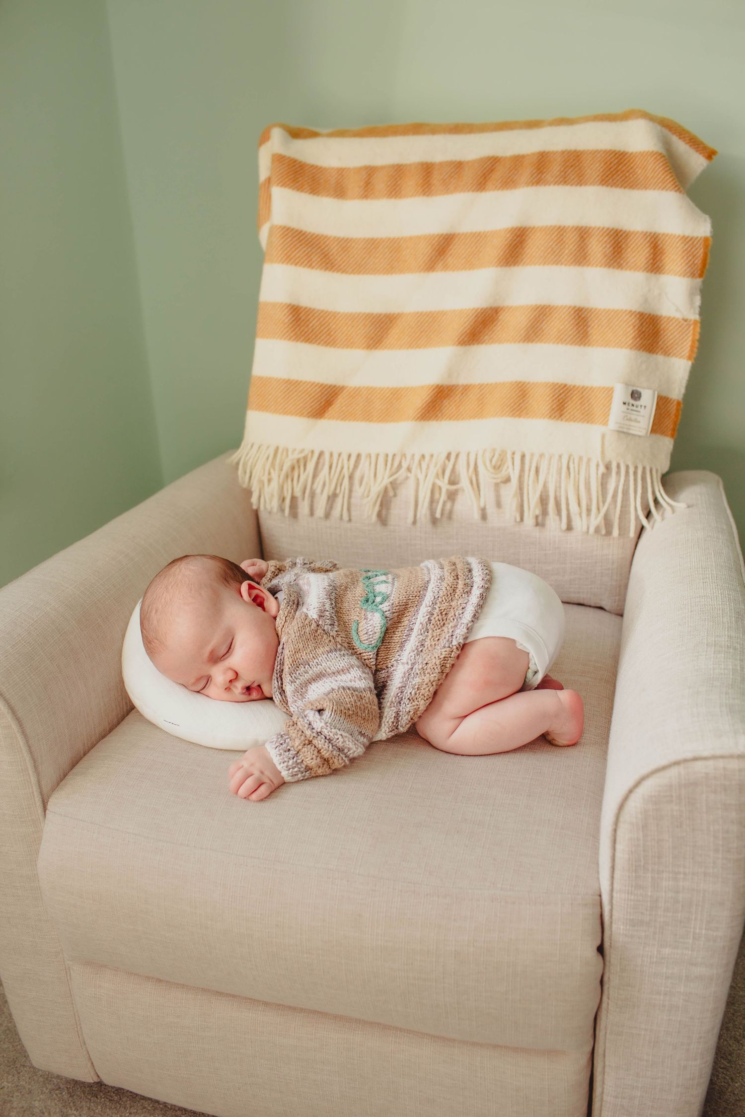 A series of photos showing a sleeping baby in a knit romper resting peacefully on a beige couch with striped throw pillow.