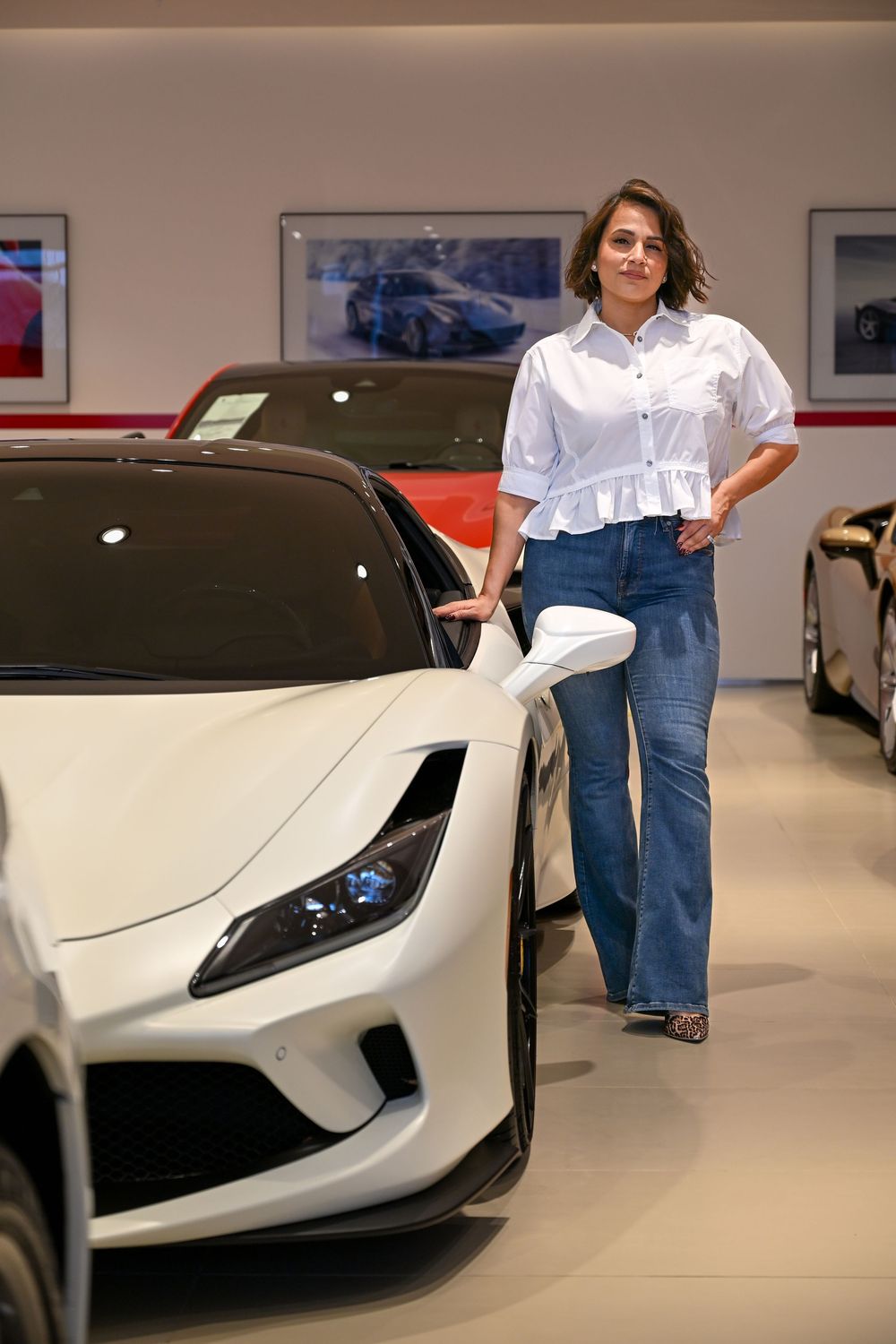 A white Ferrari sports car displayed in a sleek modern showroom with polished floors.