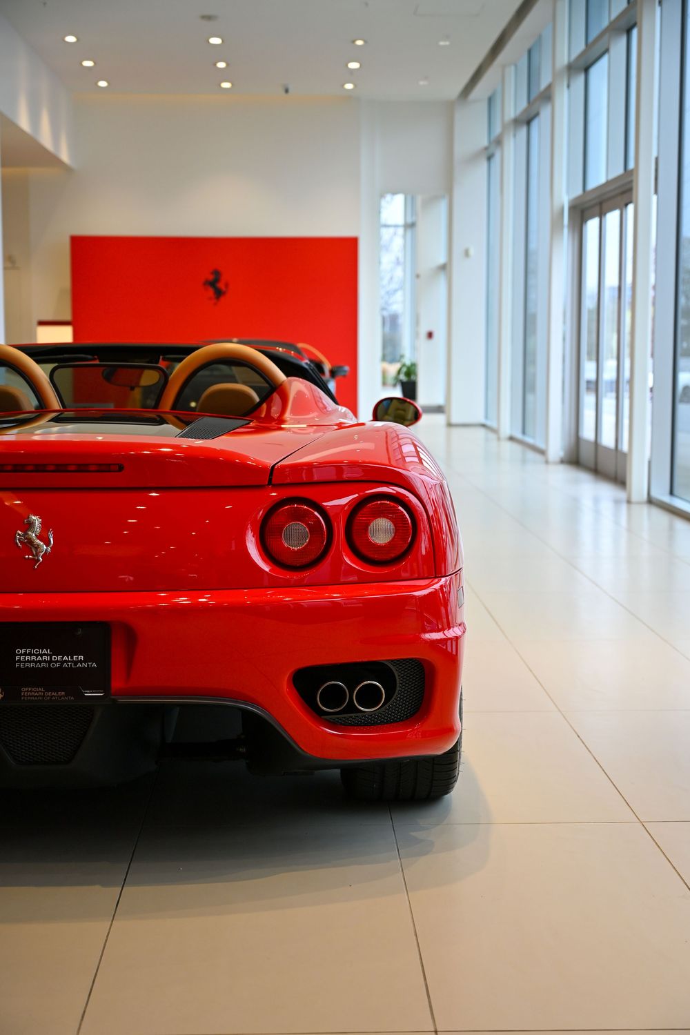 A series of four red Ferrari sports car tail light and rear view detail shots in a modern dealership showroom.