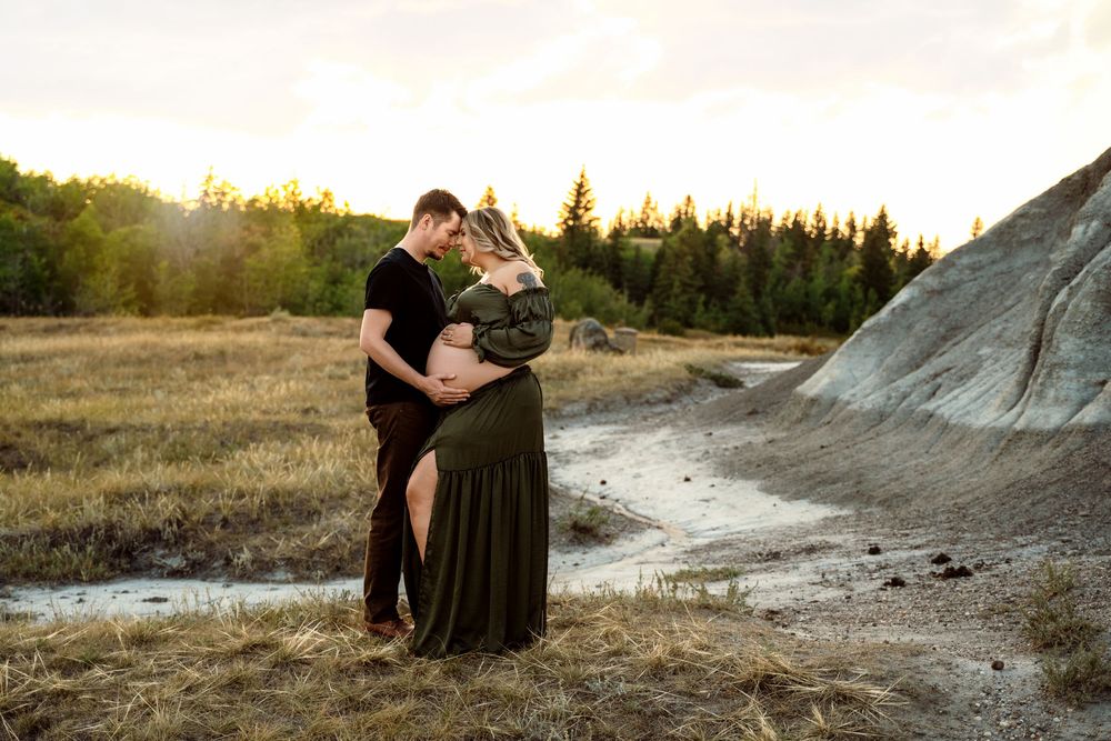 A couple shares a romantic sunset moment on a grassy mountain overlook, their silhouettes highlighted against the golden sky.