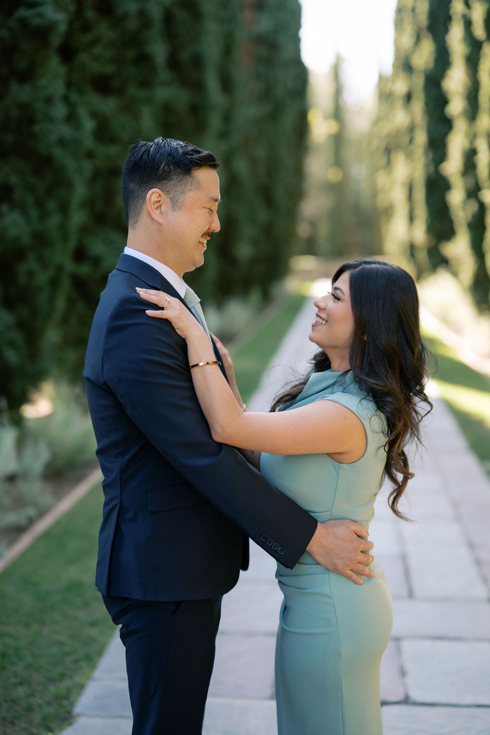 A couple in formal attire share a romantic moment on a tree-lined path in a series of candid photos.