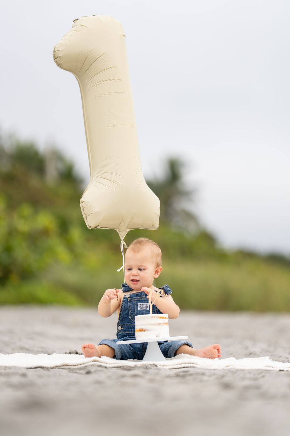 A sequence of three photos shows a baby in overalls sitting on a beach with a beige balloon floating upwards.