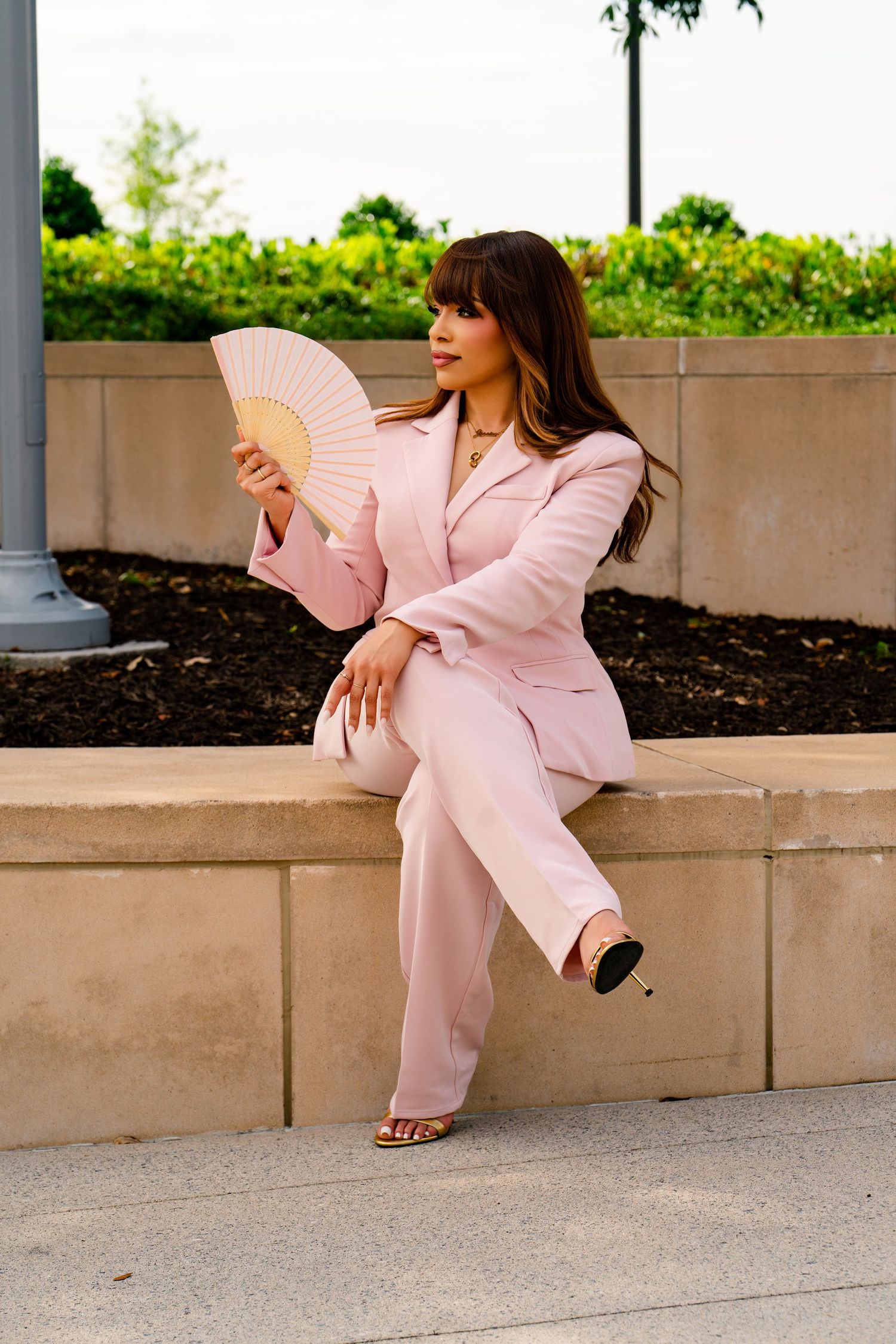 A person in a brown suit sits elegantly on the edge of a decorative mosaic fountain in an upscale setting.