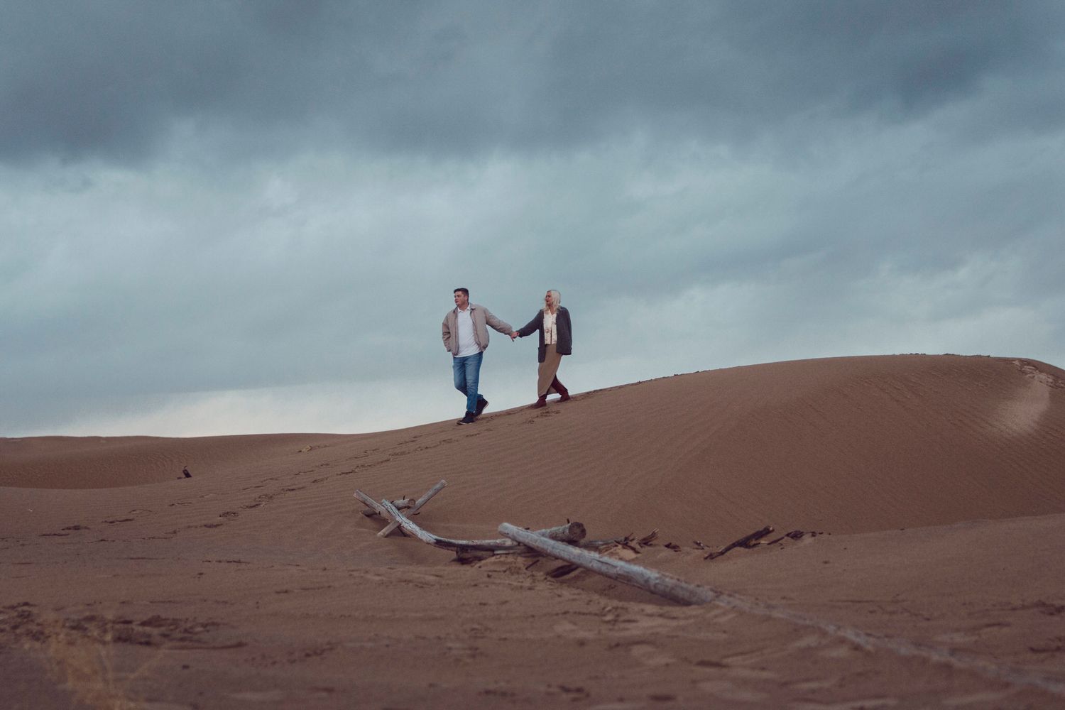 Visiting couple explore sand dunes during a shoulder season spring day date couples portrait session near Kingston Ontario
