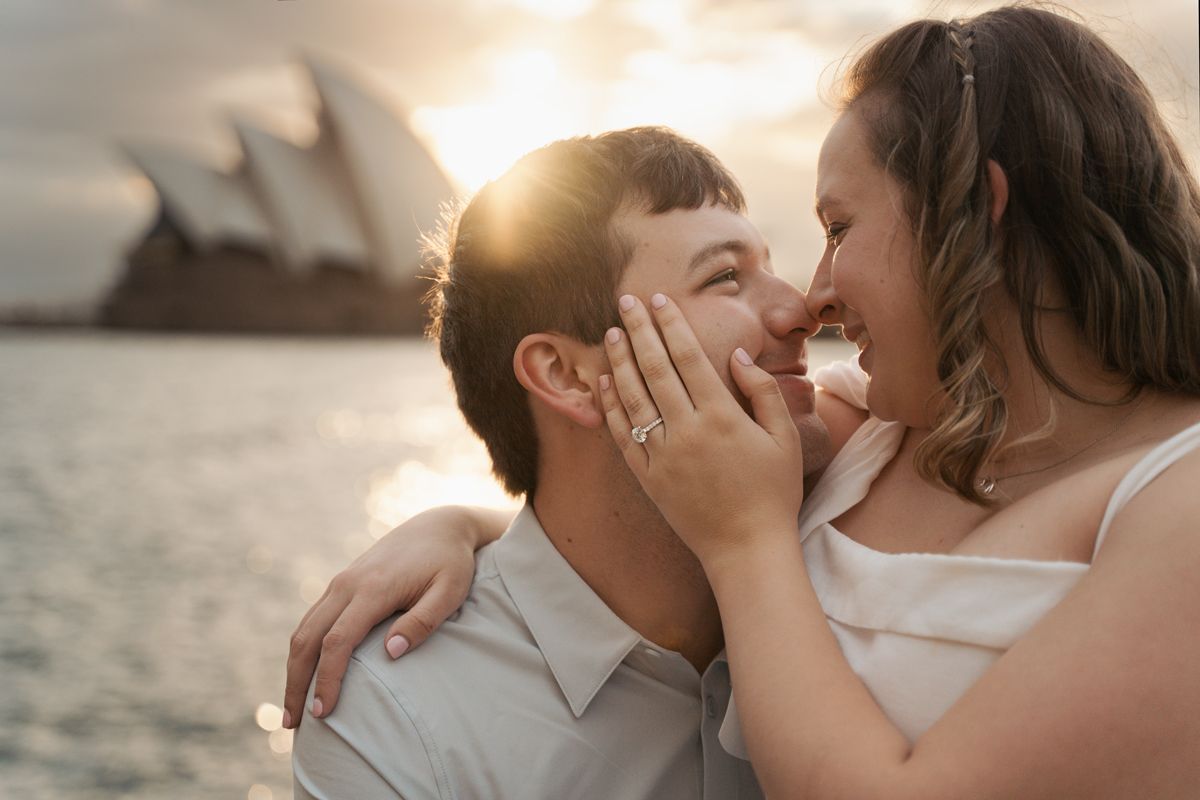 A romantic couple shares an intimate moment at sunrise during an engagement photoshoot at the rocks in sydney