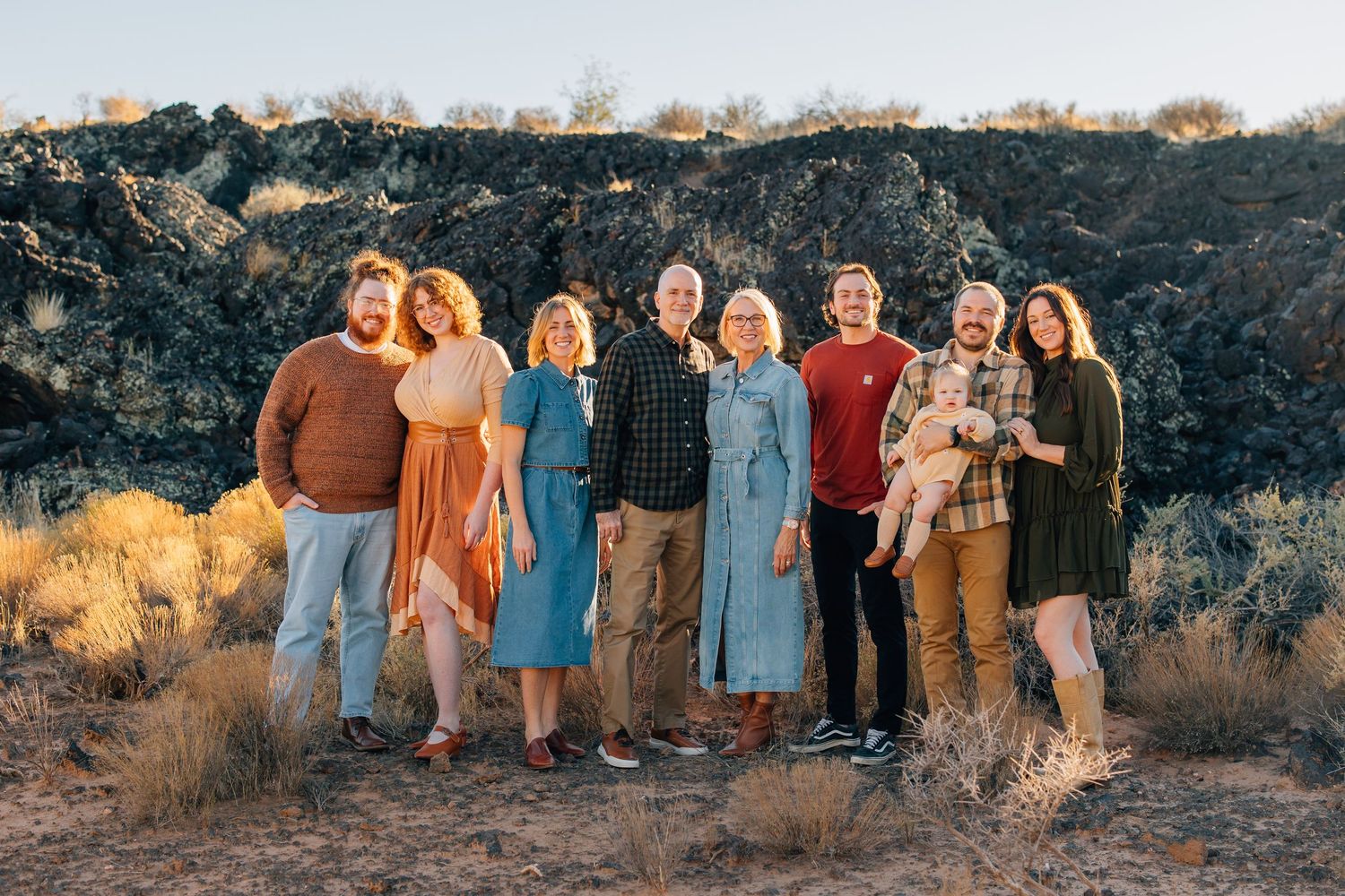 A group in coordinating blue and white outfits poses together on a sunlit hillside during golden hour.