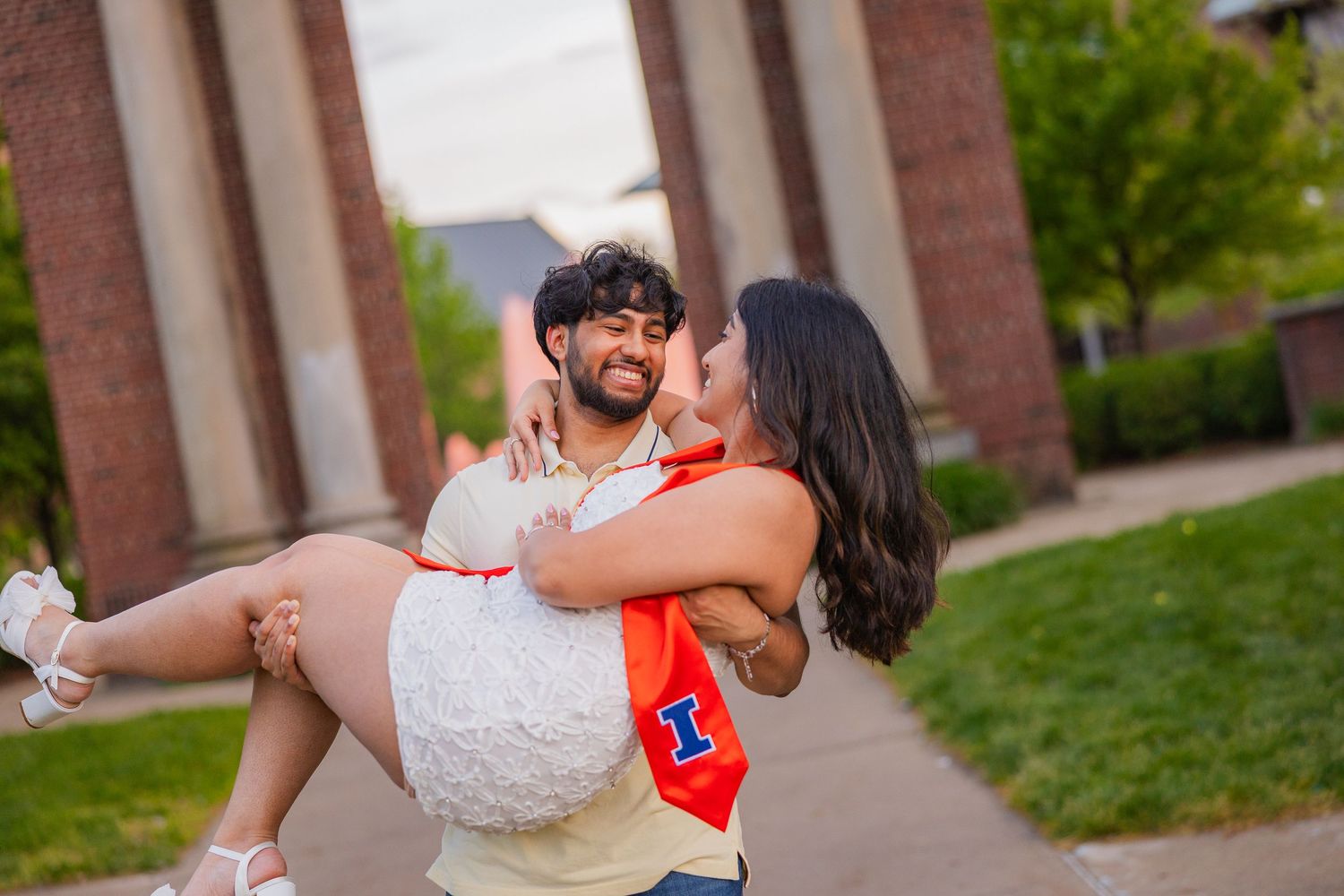 UIUC student holding his girlfriend up and laughing together at Hallene Gateway