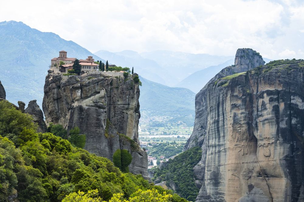 Panoramic view of Meteora's towering rock formations with ancient monasteries perched atop steep cliffs in Greece.
