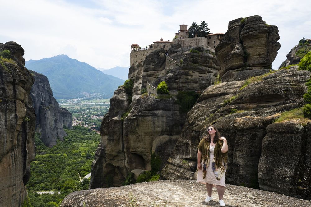Scenic view of towering rock formations at Meteora in Greece with mountains and valley in the background.