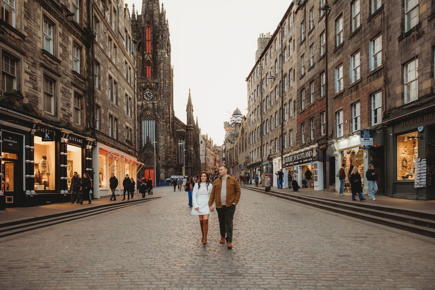 Historic buildings line the steep cobblestone Royal Mile street in Edinburgh's Old Town at sunset.