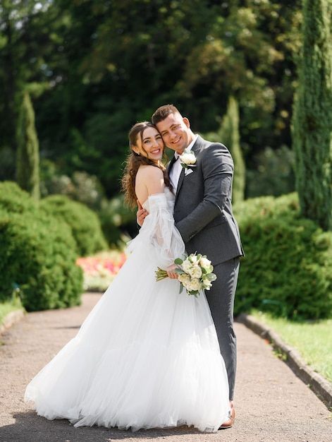 A romantic wedding couple embraces on a garden path surrounded by lush greenery on their special day.